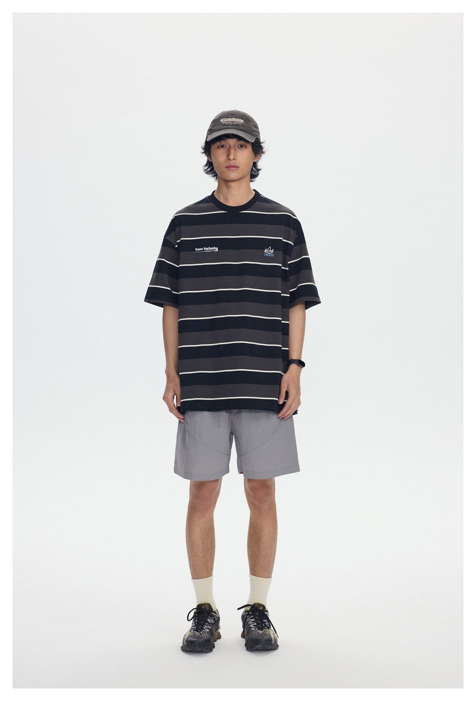 Front view of a model wearing an oversized black and charcoal striped T-shirt with small chest graphics.