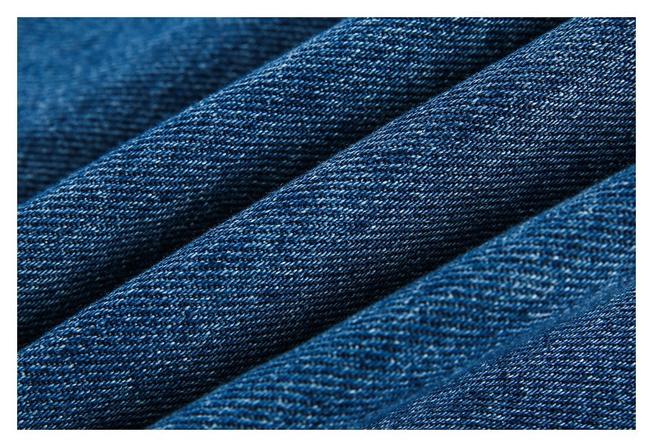 Close-up of dark blue denim fabric with a visible diagonal twill weave.