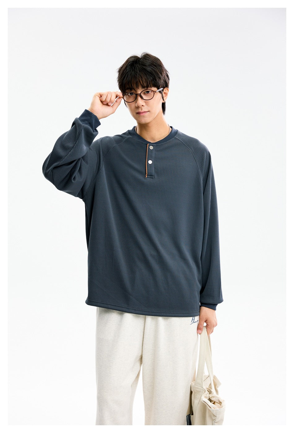 Closer view of a model wearing a slate blue ribbed henley with raglan sleeves, contrast placket trim and white buttons.