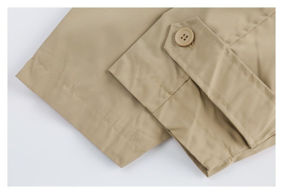 Close-up of a beige garment sleeve cuff with a matching button and visible stitching.
