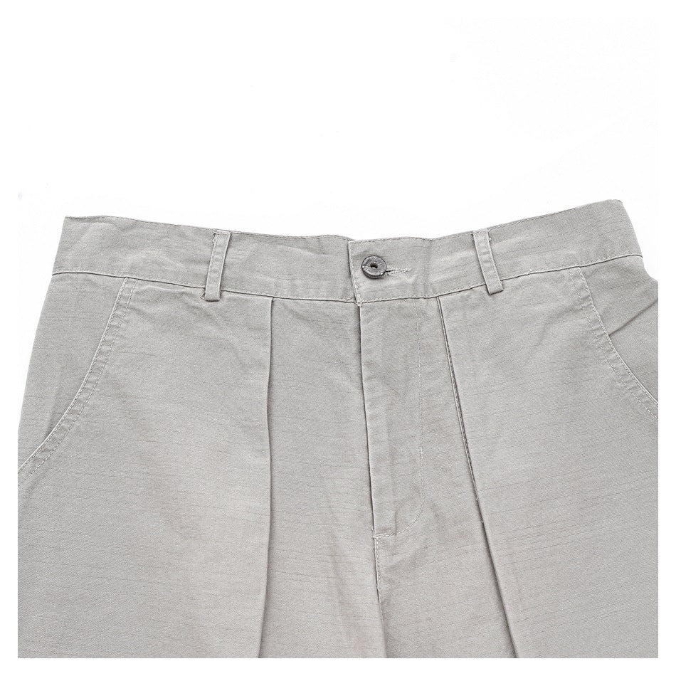 Close-up of the trousers' front waistband, button, belt loops, pleats, and curved pocket openings.