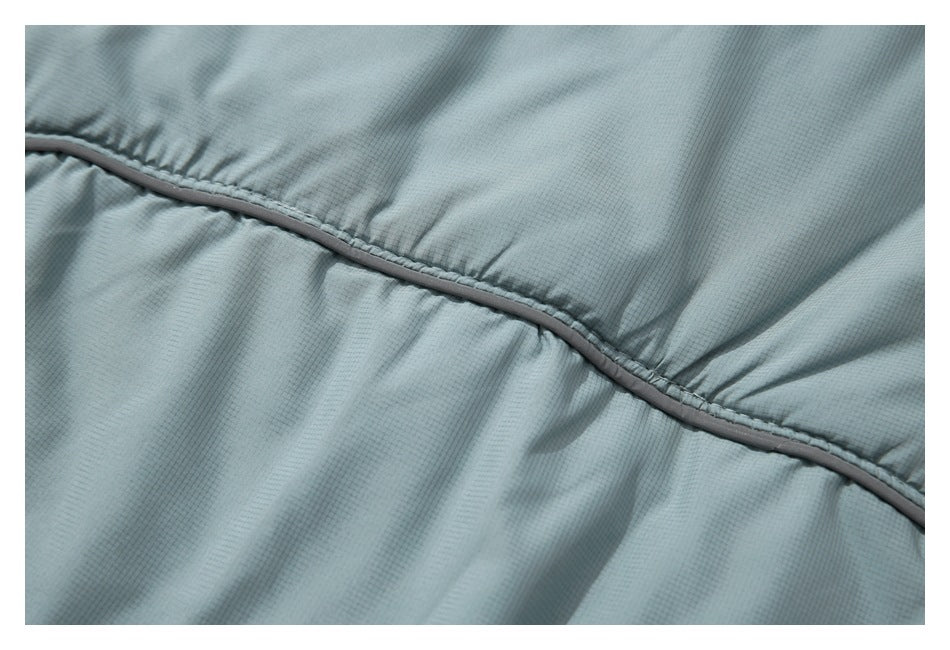 Close-up of gathered pale blue-gray fabric joined by a narrow contrasting piped seam.