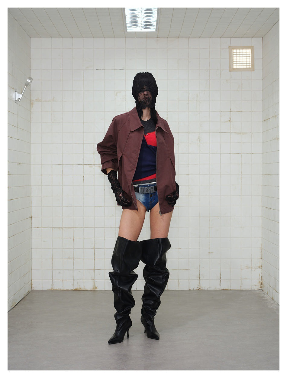 Front view of a model in a burgundy jacket with a wide collar and zip closure, styled with shorts and tall black boots.