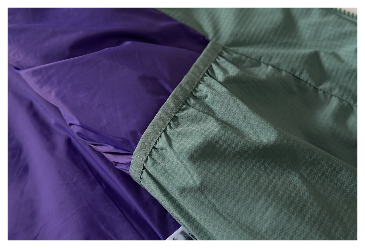 Close-up of the purple lining joined to the textured sage-green jacket shell at a seam.