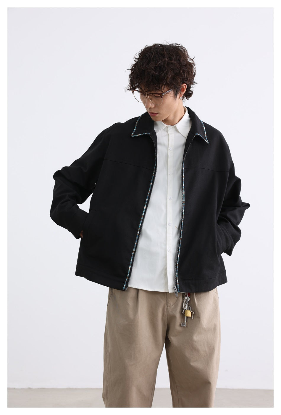 Model wearing a black zip-front jacket with multicolor trim on the collar and zipper, over a white shirt.