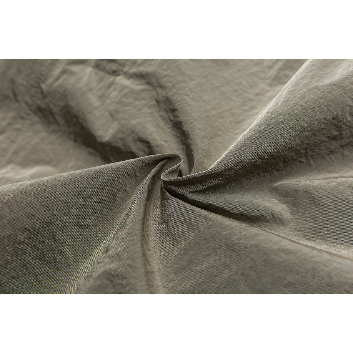 Close-up of the crinkled olive-gray shorts fabric and a folded seam.
