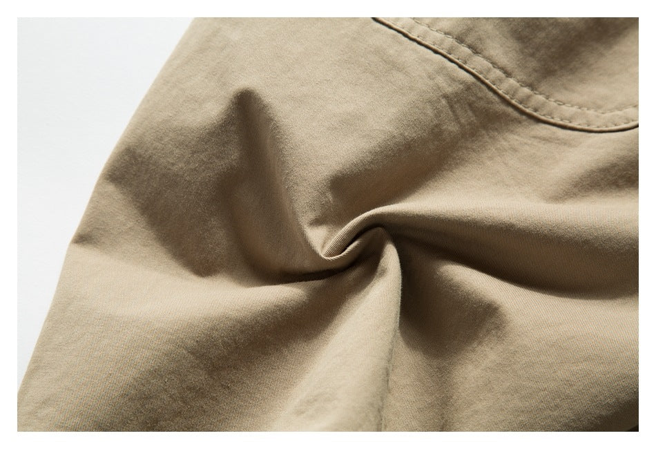 Close-up of beige shorts fabric with a curved stitched seam and soft folds.