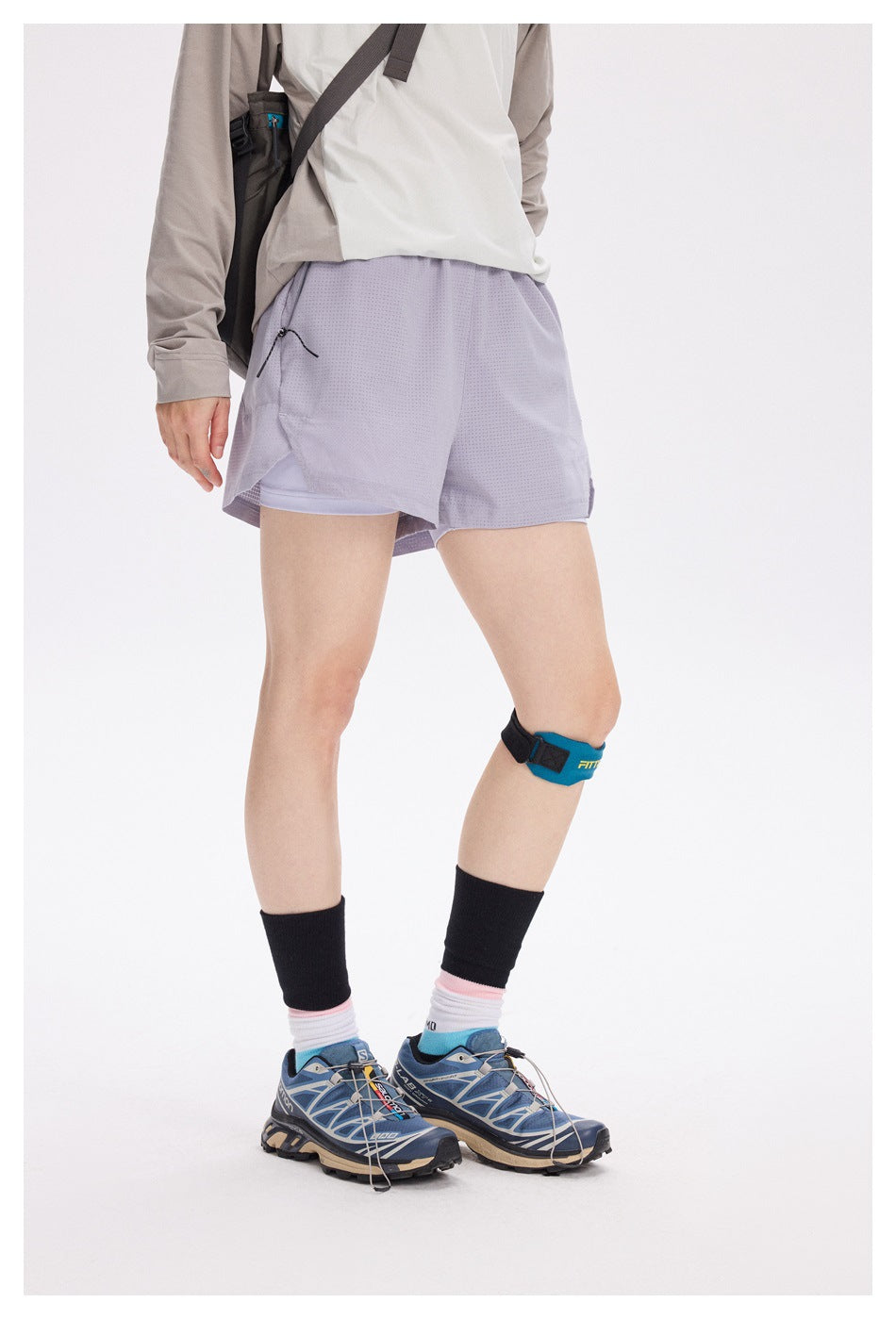 Model wearing pale lavender running shorts with a perforated outer layer, built-in liner and zippered side pocket.