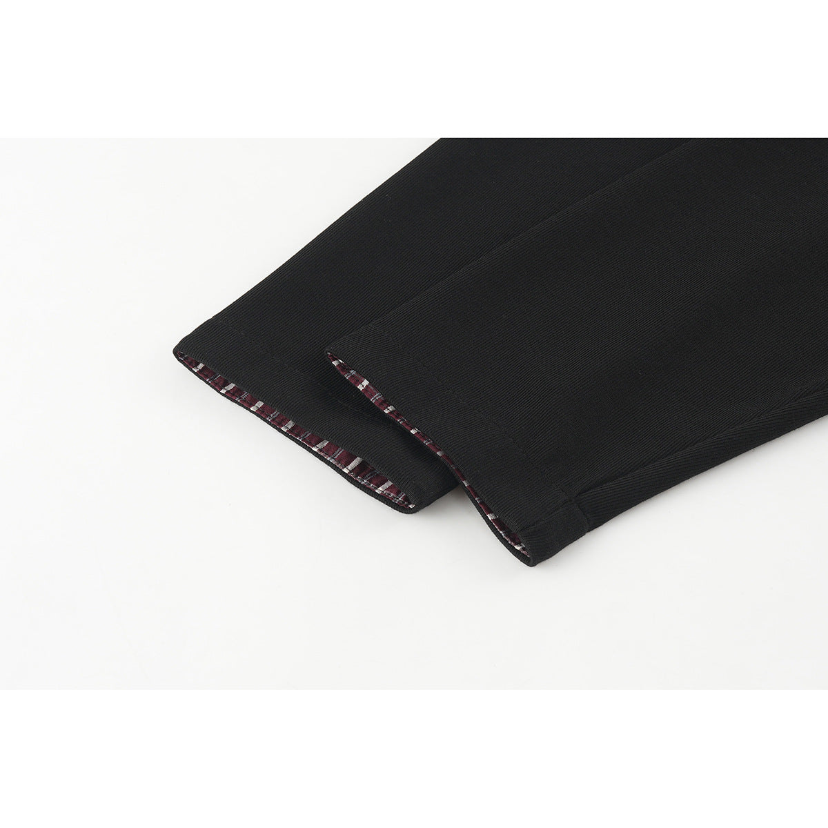 Close-up of black sleeve cuffs edged with red-and-white plaid fabric.
