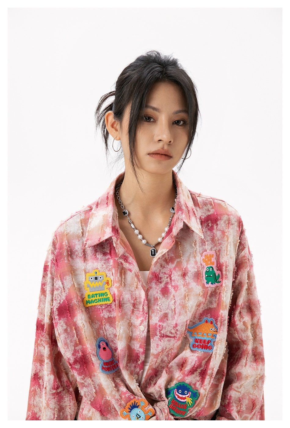 Close view of the pink patterned shirt's collar, buttons and colorful cartoon patches on the front.