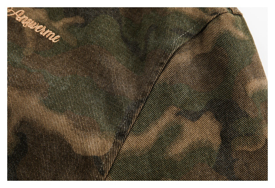 Close-up of a camouflage garment's shoulder seam and partial tan embroidered script.