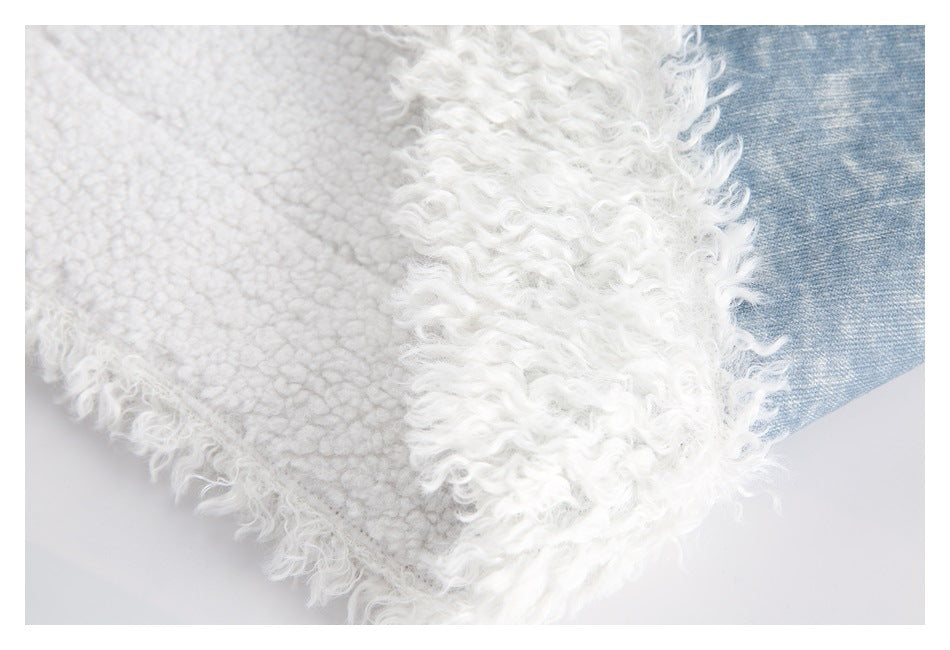 Close-up of the jacket's white fleece lining and curly trim beside blue fabric.