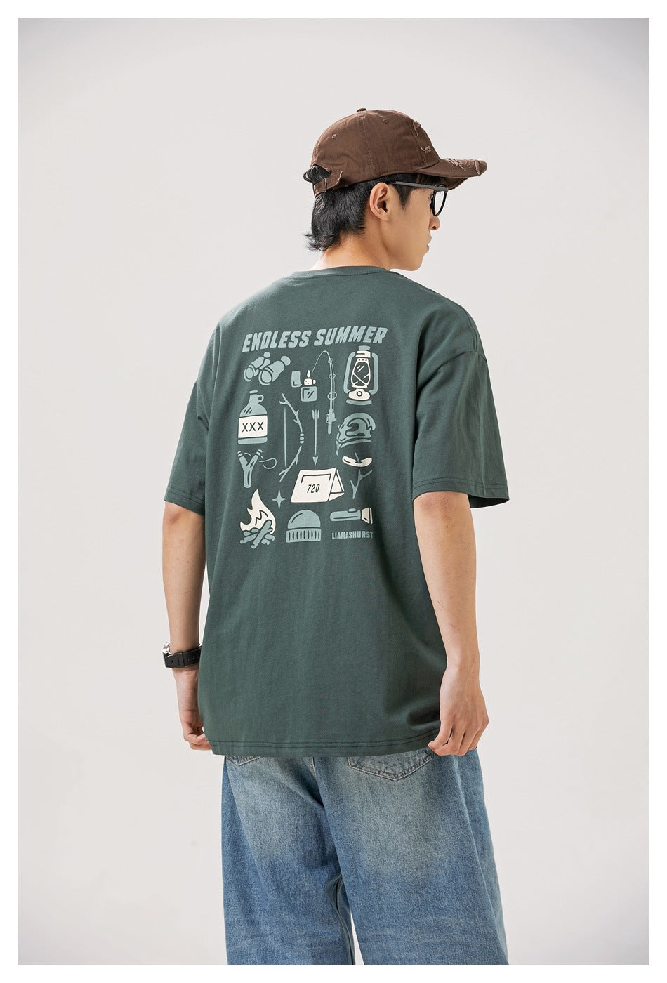 Back view of a model wearing a dark green T-shirt with a large camping-themed graphic.