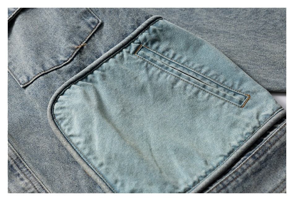 Close-up of a large light blue denim pocket with rounded piped edging and tan topstitching.