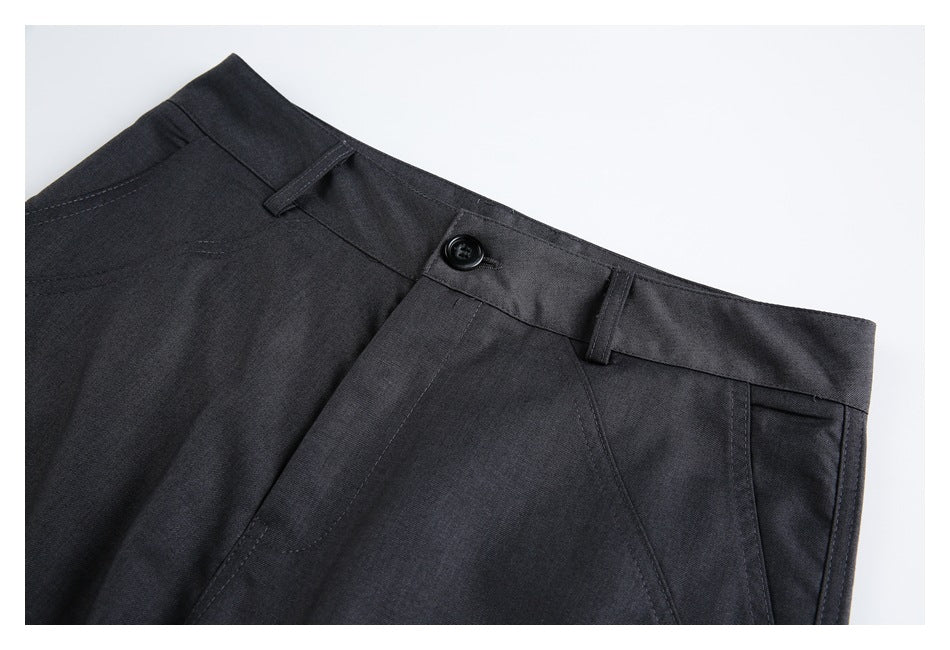 Close-up of charcoal trouser waistband, button, belt loops, and angled front pocket.