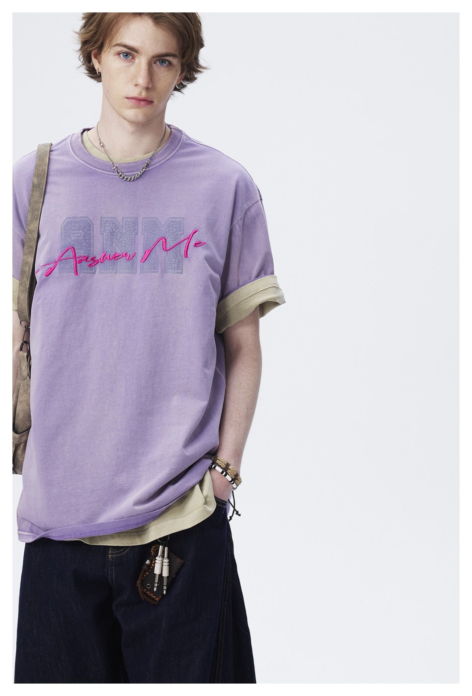 Model wearing an oversized lavender T-shirt with beige rolled cuffs and a pink-and-gray chest graphic.