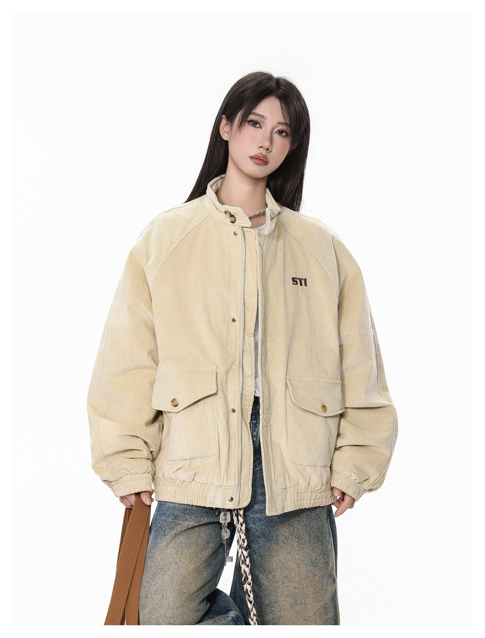 Model wearing khaki corduroy jacket zipped partly open, showing flap pockets and elastic hem, close-up