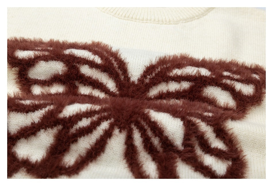 Close-up of a cream knit sweater with a raised dark brown butterfly motif.