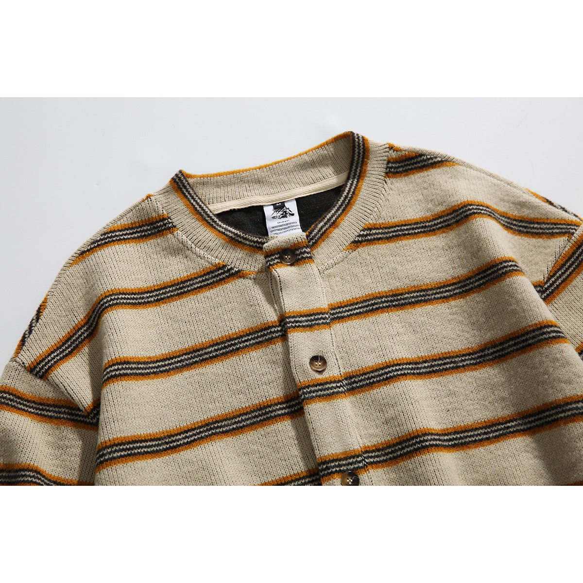 Close view of a beige knit cardigan with horizontal mustard and charcoal stripes, a button placket and ribbed collar.