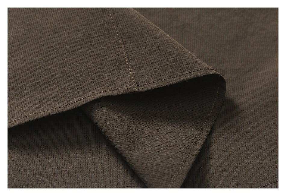 Close-up of overlapping dark brown garment fabric with stitched edges.