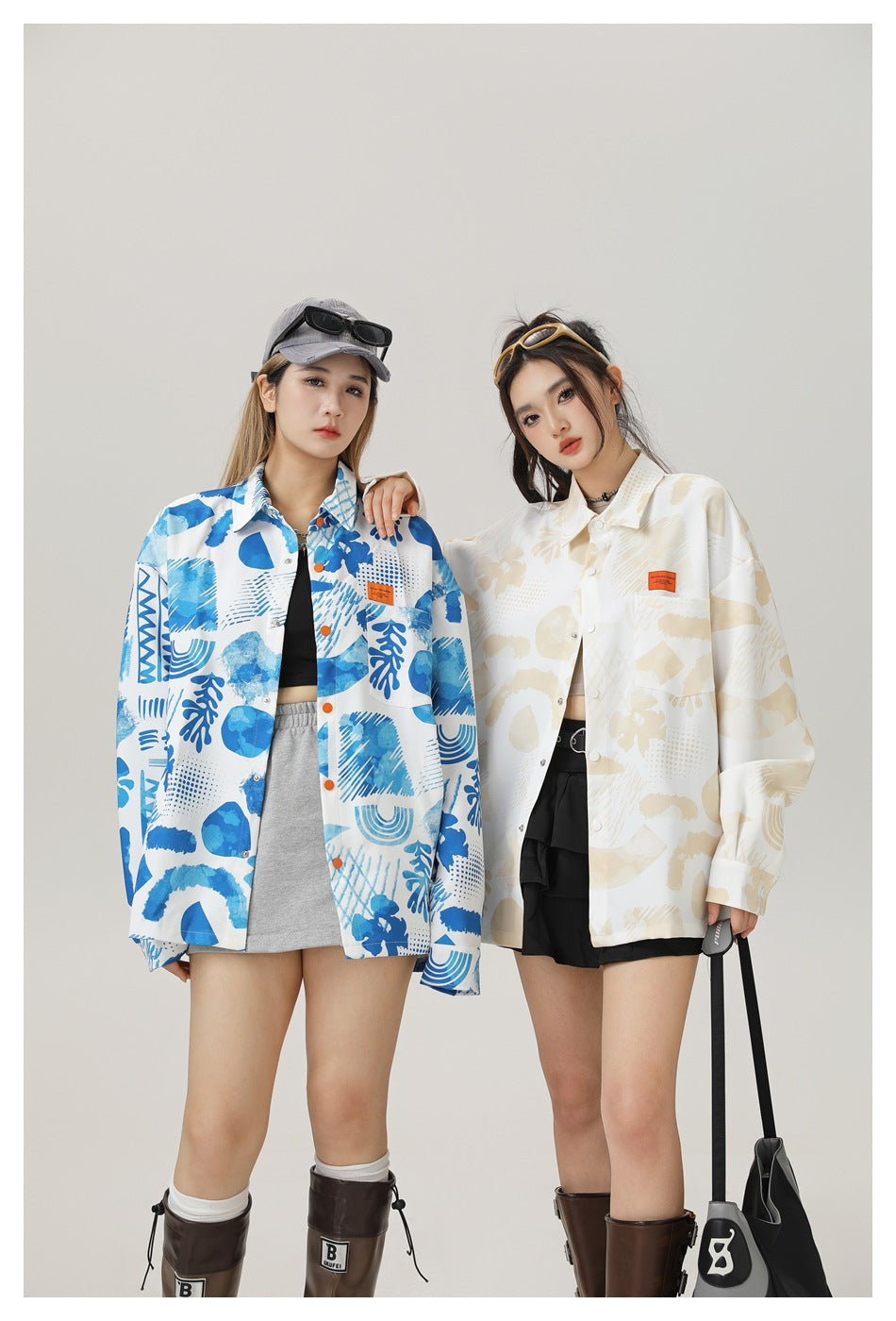 Two models wearing oversized printed button-front shirts in blue and cream with skirts and boots