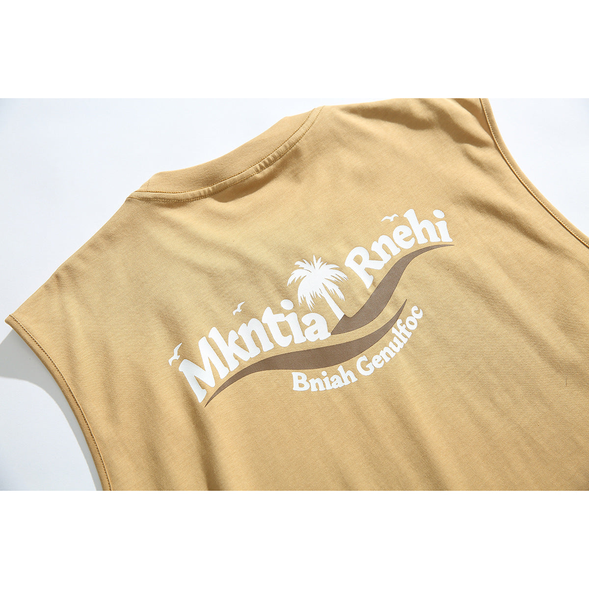 Close-up of a large white palm-tree and lettering graphic on the back of a tan sleeveless shirt.