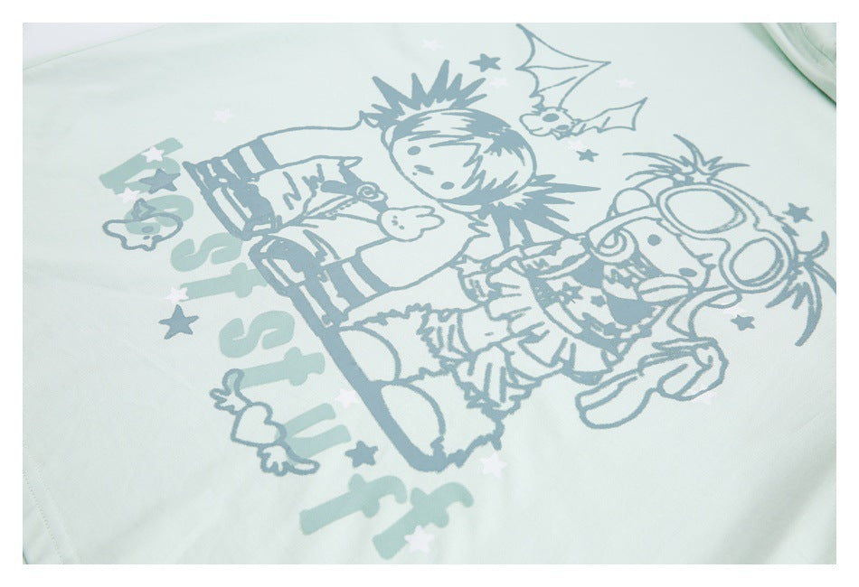 Close-up of a pale mint garment printed with blue-gray cartoon characters, stars, and decorative lettering.