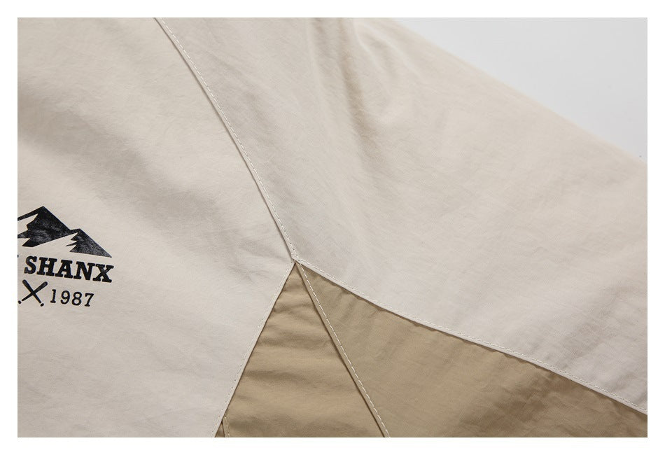 Close-up of the jacket's light beige and tan color-block panels with visible seam stitching.