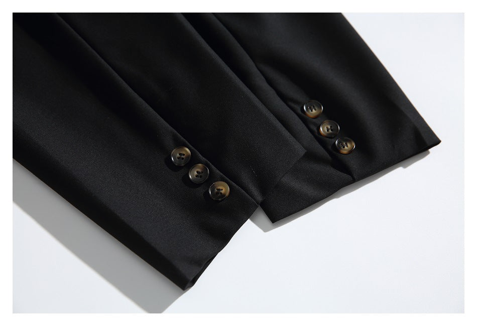 Close-up of a black blazer's sleeve cuffs, each finished with three dark buttons.