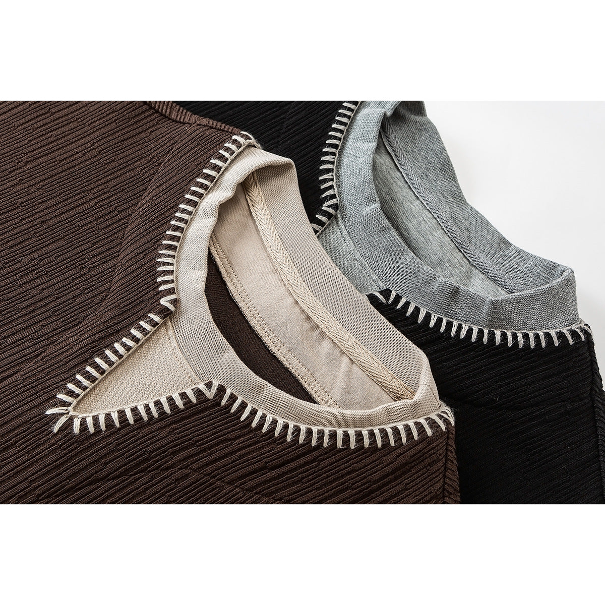 Close-up of brown, black, and gray ribbed tops with contrasting blanket-stitched neckline trim.