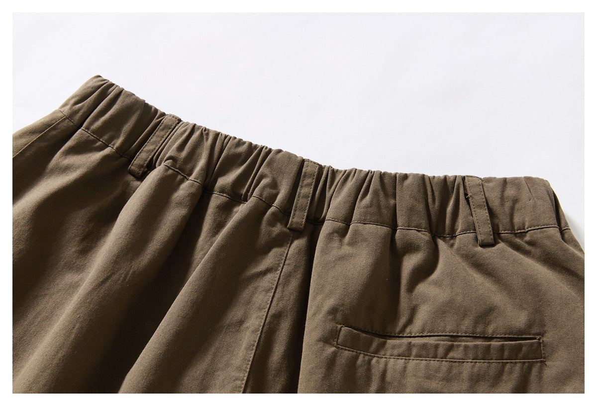 Close-up of the back of brown trousers, showing the gathered waistband, belt loops, and a welt pocket.