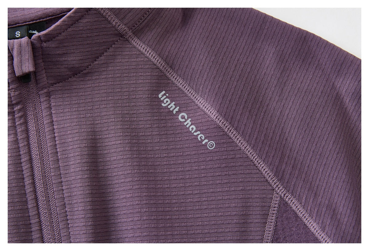Close-up of a purple ribbed jacket with a zipper, panel seams, and white lettering on the fabric.