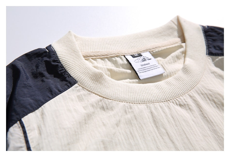 Close-up of the ribbed ivory crew neck, navy shoulder panel, and sewn garment label.