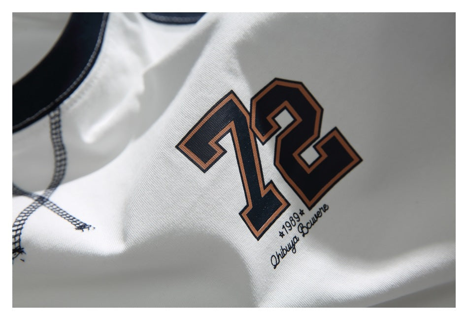 Close-up of the shirt’s navy and brown 72 chest graphic on white fabric.