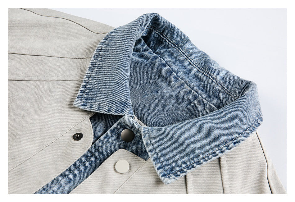 Close-up of a light gray jacket with a contrasting blue denim collar and black and white snap buttons.