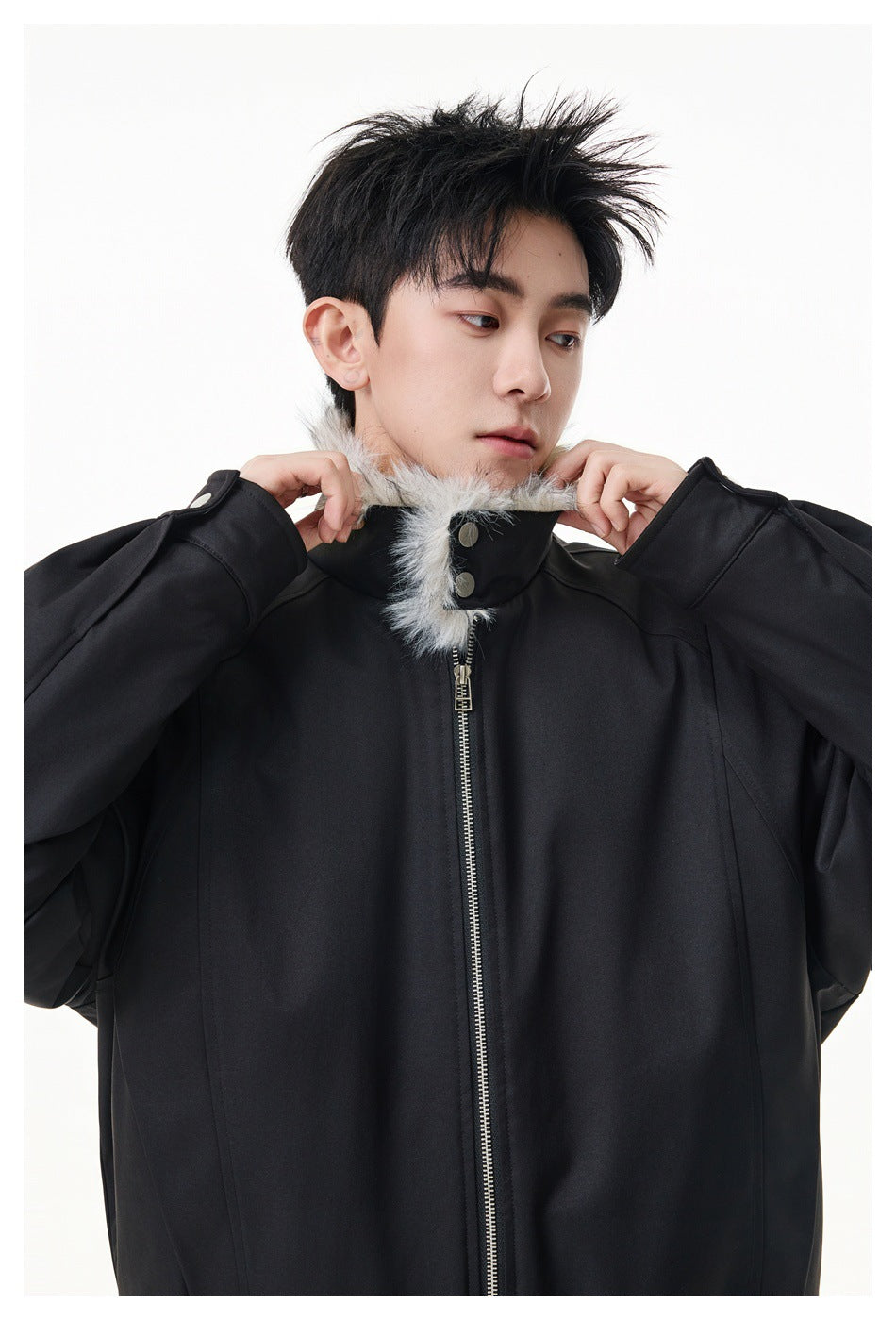 Close-up of a model adjusting the light gray fur trim on the black jacket's zip-front collar.