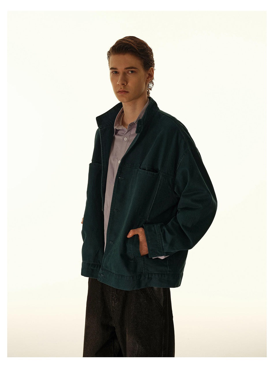 Closer three-quarter view of a model wearing a dark teal jacket with roomy pockets over a mauve shirt.