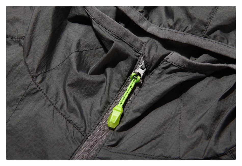 Close-up of the charcoal jacket's front zipper with a bright green pull and surrounding hood and chest seams.