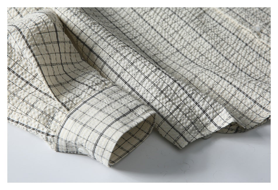 Close-up of the cream shirt's black windowpane check, textured fabric, and buttoned cuff.