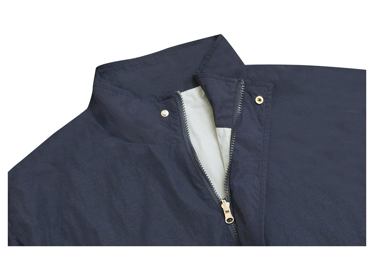 Close-up of a dark navy jacket collar with a partly open zipper, pale lining, and metal snaps.