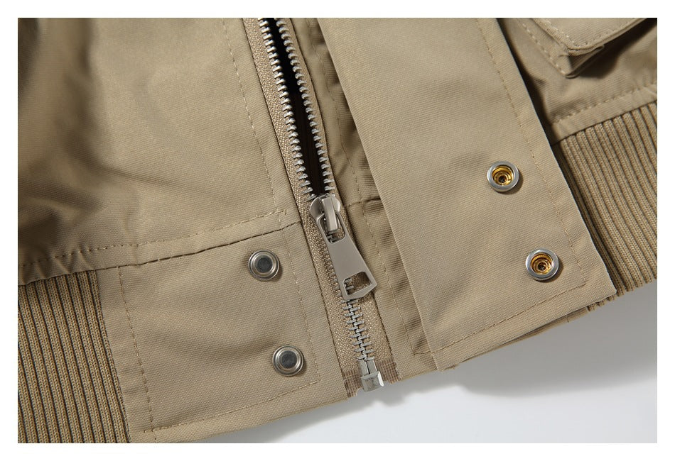 Close-up of the beige jacket's front zipper, snap placket, and ribbed hem.