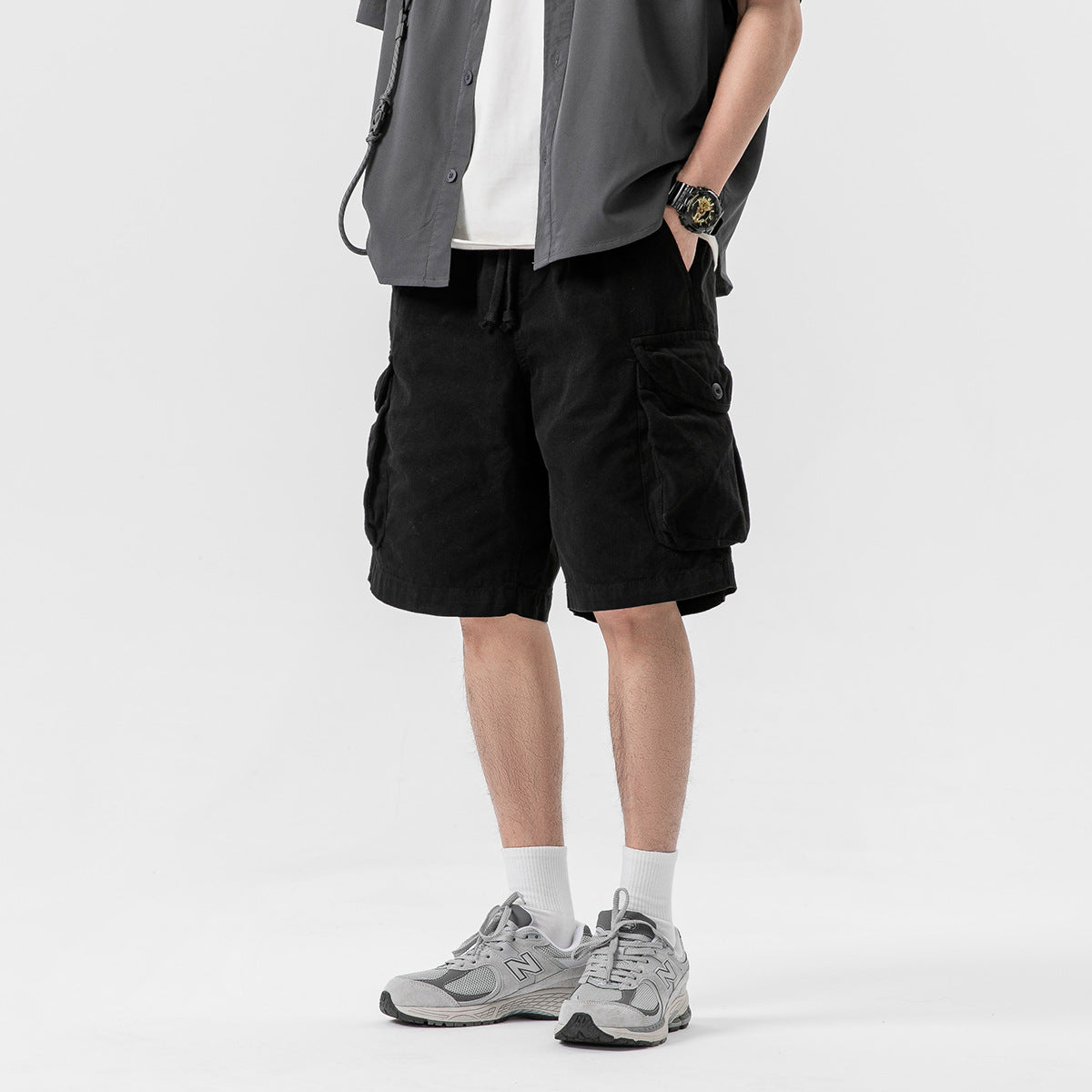 Model wearing black cargo shorts with an elastic drawstring waist and large flap pockets, shown from the front at an angle.