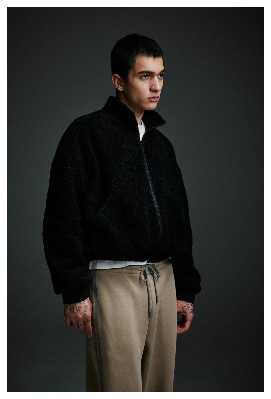 Three-quarter view of a model wearing a black zip-up fleece jacket over a white shirt.