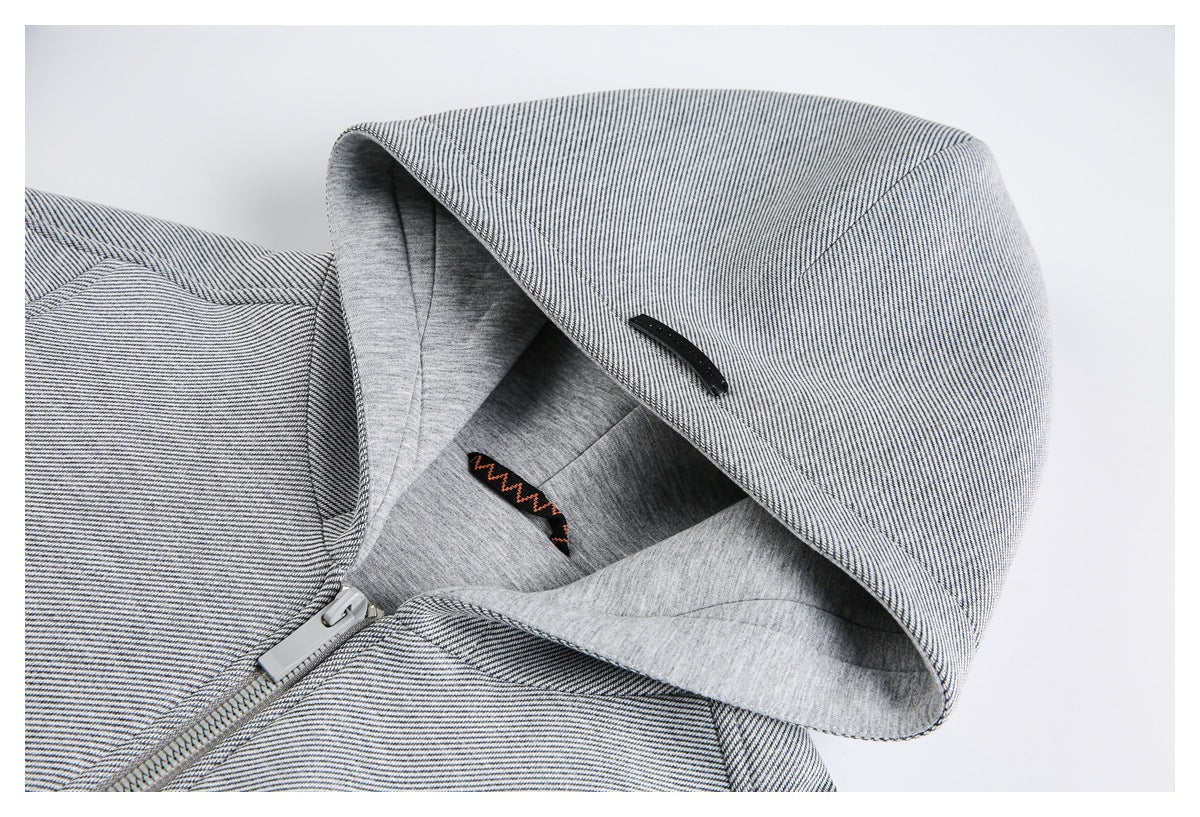 Close-up of a light gray striped jacket hood, gray lining, black tab, and front zipper.