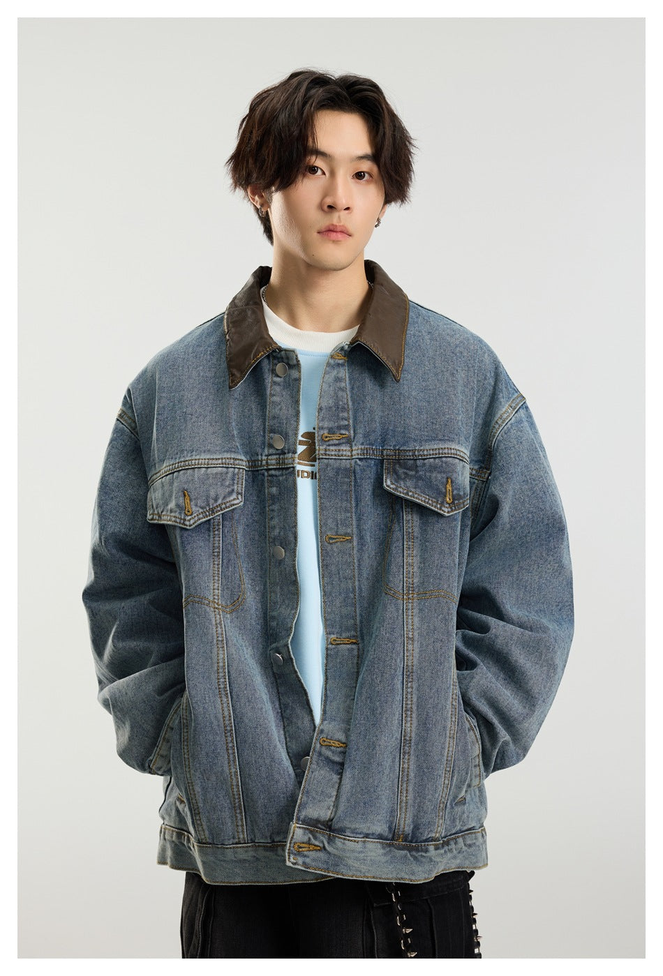 Close-up of a model wearing a blue denim jacket with brown collar, chest flap pockets and button front
