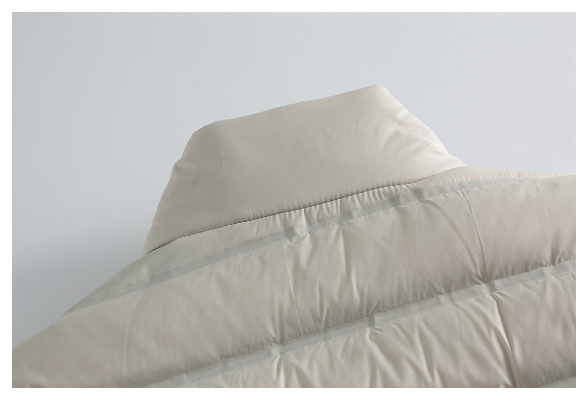 Close-up of the raised collar and quilted panels of a cream puffer jacket.