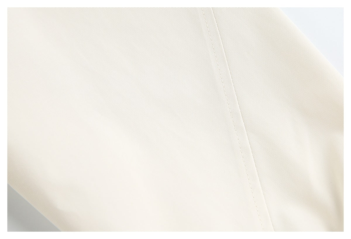 Close-up of smooth ivory garment fabric and a single curved seam.