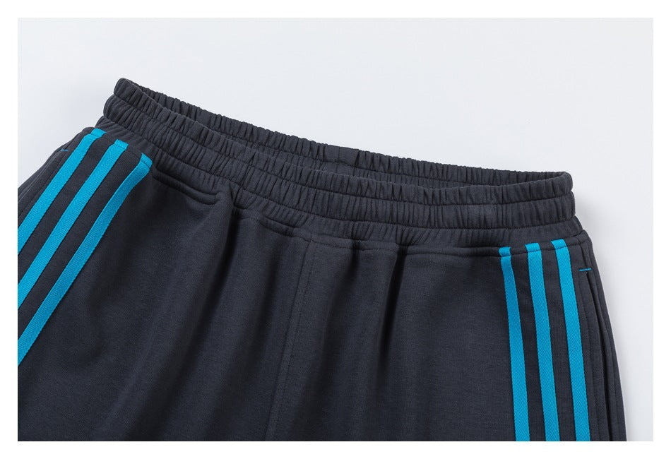 Close-up of charcoal shorts with an elastic waistband, pockets, and bright blue side stripes.