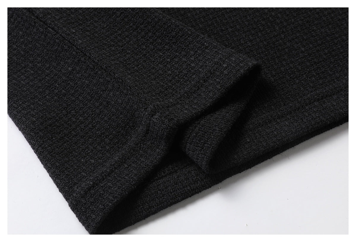 Close-up of black textured fabric with a folded edge against a white background.