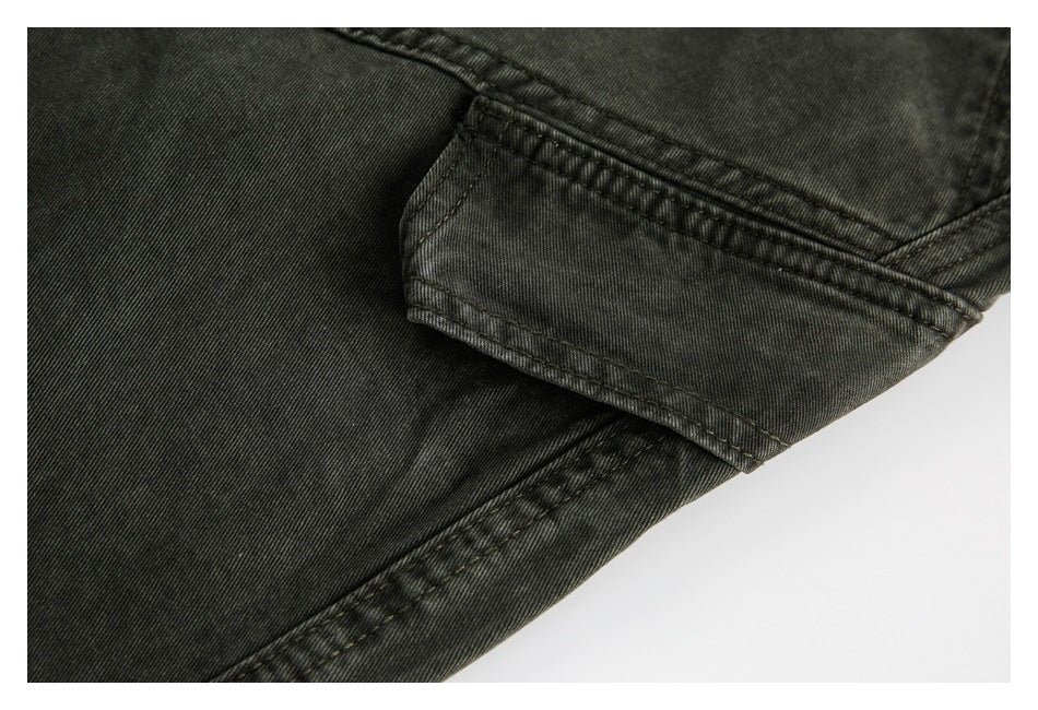 Close-up of a stitched pocket flap and seams on charcoal trousers.